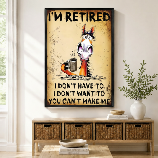 Black framed retro grunge funny retired horse coffee canvas art with bold I'm Retired lettering above a startled wide-eyed cartoon horse with disheveled mane holding a steaming metal coffee cup and the cheeky retirement quote I Don't Have To I Don't Want To You Can't Make Me on a heavily distressed aged amber rust-textured background, displayed on a white wall above a light wood rattan basket storage console with a white ceramic bowl, stacked books, and a white vase of greenery in a bright sunlit entryway
