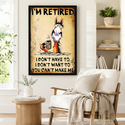 Black framed retro grunge funny retired horse coffee canvas art showing bold I'm Retired text above a startled wide-eyed cartoon horse with a tangled mane holding a hot steaming metal coffee mug with the humorous retirement quote I Don't Have To I Don't Want To You Can't Make Me on a distressed aged yellow-brown rust-mottled background, displayed on a white wall beside a white wooden armchair with a cream fringed throw and a round wood side table with a book in a bright reading nook with open shelving and g