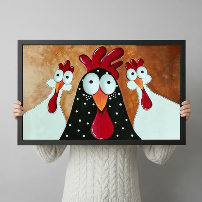 Person holding a large horizontal black framed funny rooster and two chickens canvas art print with three googly-eyed cartoon birds — a black polka-dot rooster and two white hens with bright red combs on a warm golden brown background
