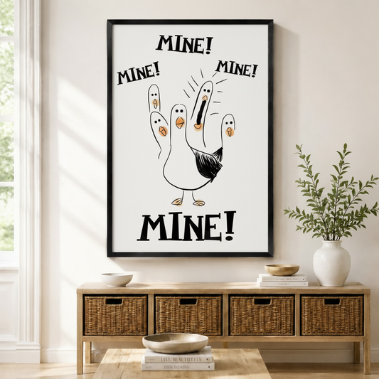 Black framed funny seagull Mine canvas art with a cartoon white seagull raising five finger-shaped baby seagulls and shouting Mine Mine Mine in bold black lettering on a clean white background, displayed above a rattan storage console in a bright entryway