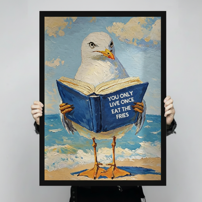 Person holding a black framed funny seagull beach quote art print showing full oil painting detail of a seagull reading a blue book with You Only Live Once Eat The Fries text against a light gray backdrop