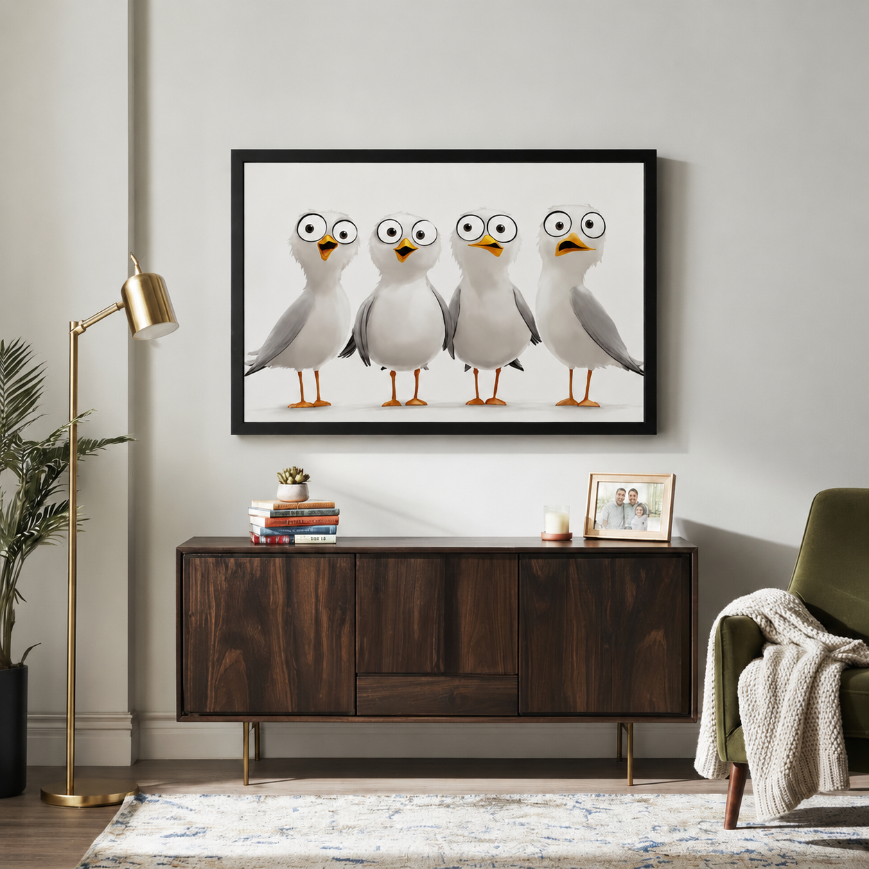 Humorous cartoon seagulls with big googly eyes black framed wall art above walnut sideboard in bright living room with gold floor lamp and green armchair
