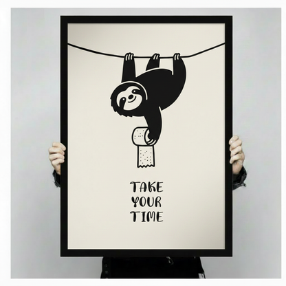 Funny sloth hanging upside down with toilet paper roll and Take Your Time quote, black framed bathroom humor poster shown in hand mockup displaying print size