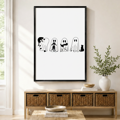 Framed canvas print featuring four whimsical ghosts interacting with black cats in a minimalist black and white line art style, displayed above a rattan storage console in a bright modern entryway