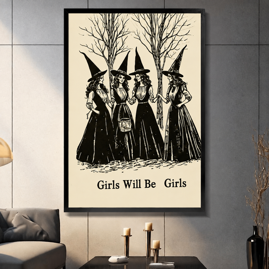 Framed gothic wall art print of four witches in black dresses with pointed hats standing among bare trees, titled Girls Will Be Girls, displayed in a modern living room above a dark coffee table with candles