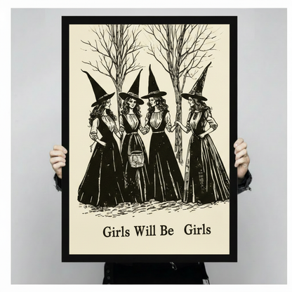 Close-up of a gothic art print being held up, depicting four witches in Victorian-style black dresses and pointed hats in a woodland scene, with Girls Will Be Girls printed in bold serif font at the bottom