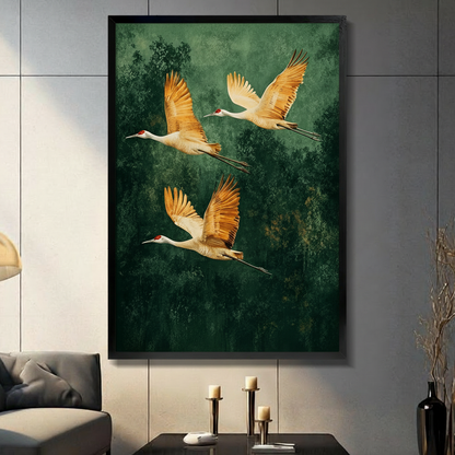 Three golden cranes soaring over dark green forest, elegant black framed wall art print displayed in modern living room with candlestick decor
