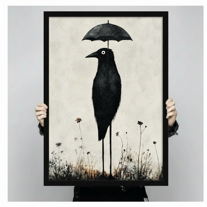 Person holding a large black framed print of a surreal gothic crow on stilted legs carrying an umbrella amid wildflowers, shown against a neutral gray background