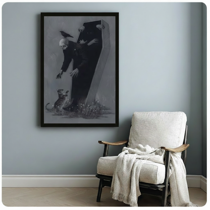 Framed gothic illustration canvas of a skull-headed figure leaning out of a dark coffin with a black crow and small animal companion surrounded by wildflowers, hung on a blue-grey wall beside a cozy linen armchair
