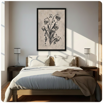 Framed gothic dark botanical skull lily of the valley canvas wall art with five skulls replacing flower blooms on a leafy stem in vintage charcoal illustration style on aged beige background hung above a wooden bed with white bedding in a sunlit bedroom