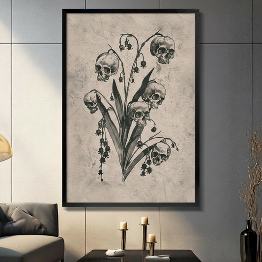 Framed gothic dark botanical skull lily of the valley canvas wall art with five human skulls replacing flower blooms on a stem with dark leaves in charcoal sketch style on aged beige background displayed on a dark grey wall in a modern living room