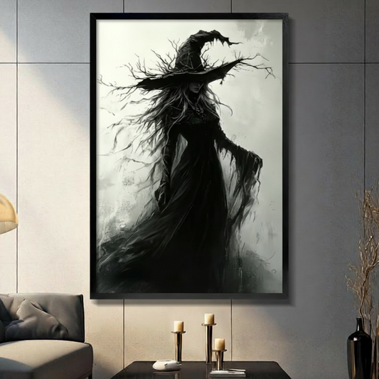Black framed gothic dark fantasy witch in a tattered black flowing gown with a wide brim hat sprouting bare dead branches and wild windswept hair merging with twisting twigs monochrome oil painting canvas wall art on misty white gray background displayed in a modern gray living room with dark sofa and metal candlesticks