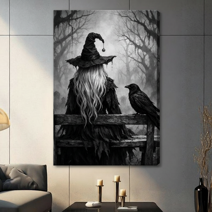 Moody gothic dark art painting of a witch seen from behind wearing a tattered wide-brim black hat with a dangling black orb and a ragged feathered black cloak with long silver-white wavy hair sitting on a weathered wooden fence beside a large black raven turning to face her against a dense misty bare-branched forest in dramatic black and white tones dark witch wall art stretched canvas in a living room with dark gray panel wall dark sofa and black vase