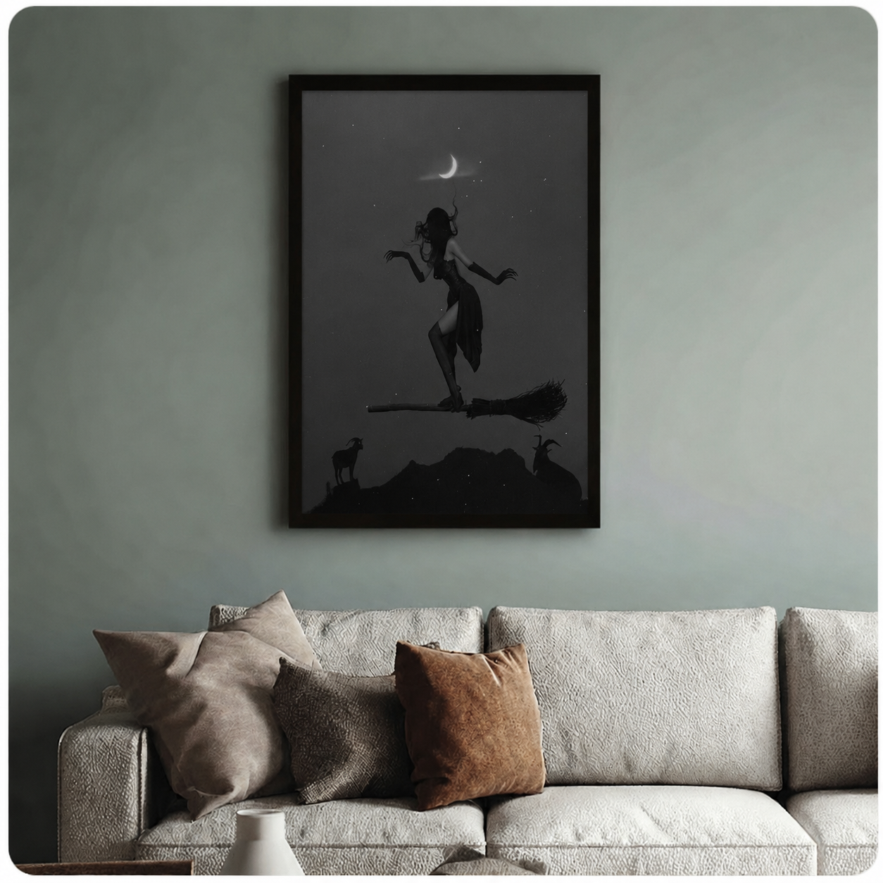 Black framed gothic witch silhouette poster above neutral sofa on sage green wall, dark fantasy wall art with starry night sky