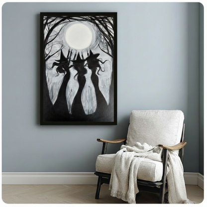 Black framed three witches moonlight silhouette canvas print hung on a soft blue-gray wall beside a white linen wood armchair with a cream knit throw blanket
