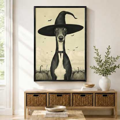 Framed canvas print of a greyhound wearing a witch hat surrounded by pumpkins and bats, displayed above a rattan console table in a bright entryway