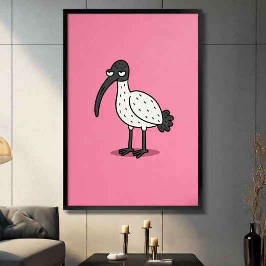 Cartoon grumpy ibis with a curved black beak on a bold pink background in a black frame, hung on a grey tiled wall above a console table with candle holders in a modern living room