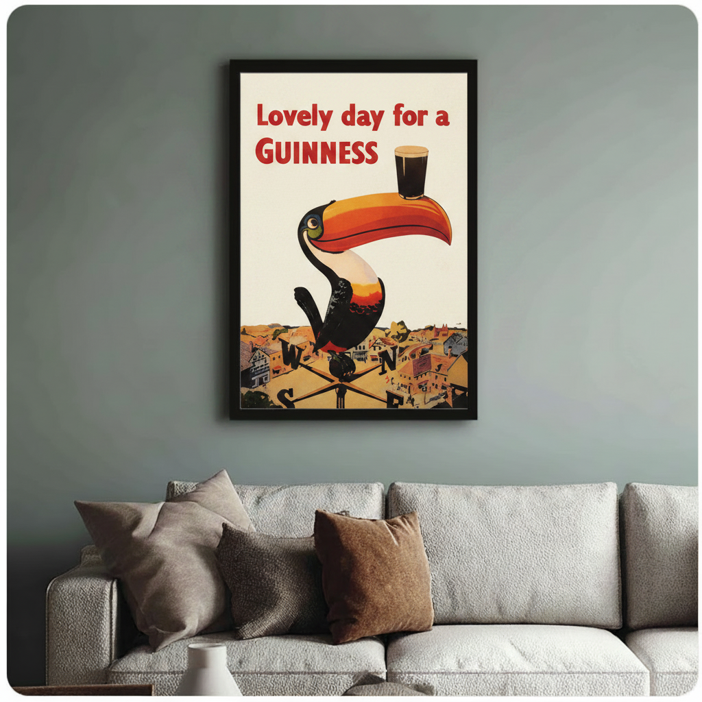 Framed classic Guinness toucan poster print above a neutral linen sofa on a blue-grey wall, vintage pub-style home wall decor
