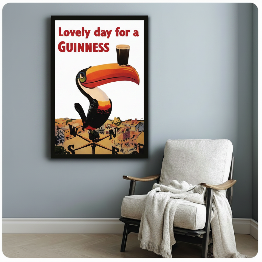 Black framed Guinness toucan retro beer advertisement wall art beside a white armchair, vintage poster print for home or bar decor