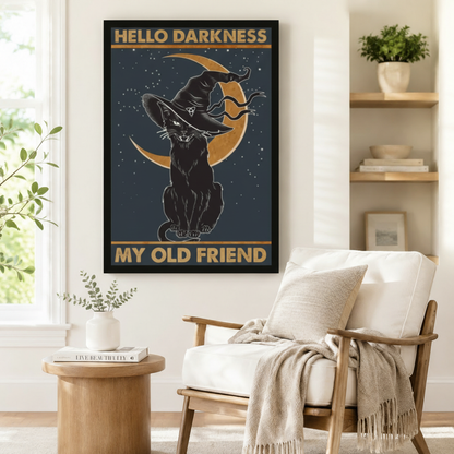 Black framed Hello Darkness My Old Friend mystical black cat witch hat moon wall art print beside white linen accent chair and round side table in cozy Scandinavian reading nook