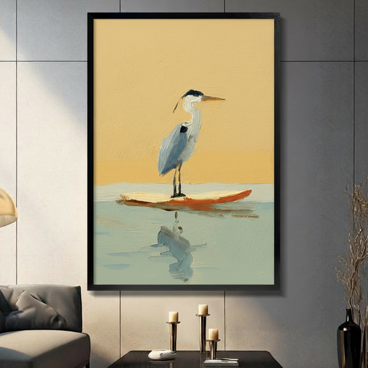 Large black framed great blue heron standing on an orange surfboard wall art print mounted on a dark grey panel wall above a console with candles