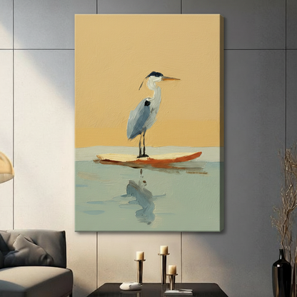 Unframed canvas wrap of a great blue heron standing on an orange surfboard with water reflection, displayed on a dark grey panel wall