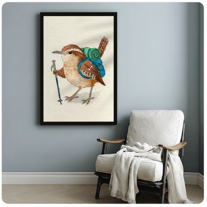 Black framed nature-themed bird wall art featuring a charming Carolina wren hiker with teal backpack and blue trekking pole, styled beside a white linen armchair on a soft blue-grey wall