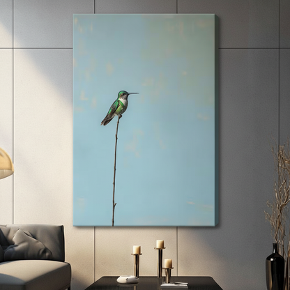 Gallery wrap stretched canvas of a green hummingbird resting on a single slender bare branch with generous negative space on a dusty blue background hung frameless on a gray wall above a dark sofa and candlesticks