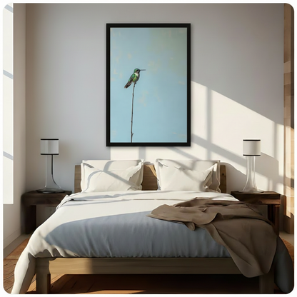 Black framed serene minimalist hummingbird on a slender branch canvas wall art with powder blue background hung above a dark wood bed with white and beige linen bedding in a sunlit Scandinavian style bedroom
