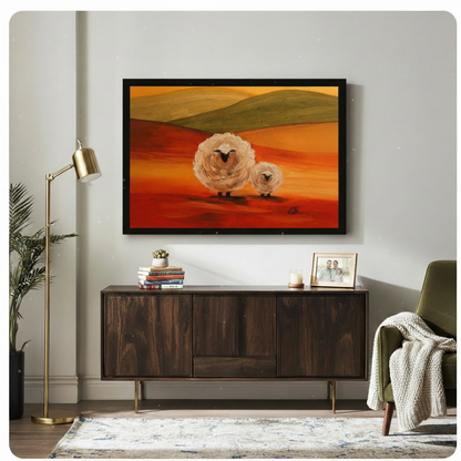 Black framed impressionist fluffy sheep duo at sunset canvas art showing a large round woolly white sheep and a smaller lamb on a sweeping vivid red-orange landscape with olive green rolling hills and a warm golden amber sky in expressive oil-paint style, displayed above a dark walnut sideboard with a gold floor lamp and olive green armchair
