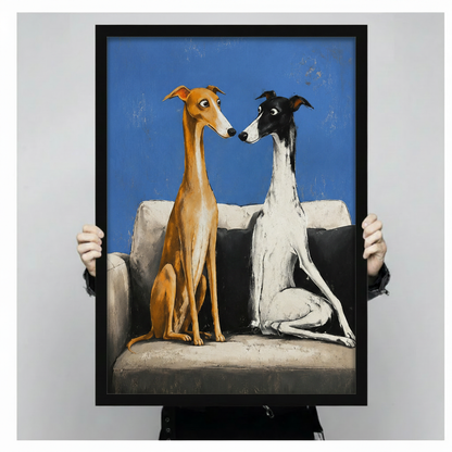 Framed canvas art print of two greyhounds on sofa with vivid blue background, held up showing full artwork detail and black frame