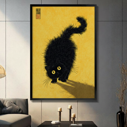 Black framed Japandi style fluffy black cat canvas art with a scruffy wide-eyed black cat with glowing yellow eyes crouching low in a stalking pose casting a long shadow on a warm golden amber textured background with a red Chinese seal stamp in the upper left corner, hung on a dark gray tiled wall above a gray sofa