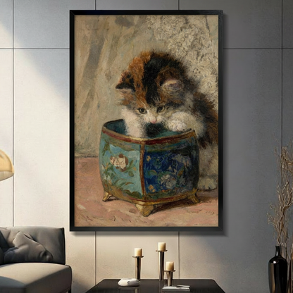 Black framed vintage calico kitten peering into a blue floral porcelain pot classical oil painting canvas wall art with warm beige background displayed in a modern gray living room with dark sofa and gold candlestick holders