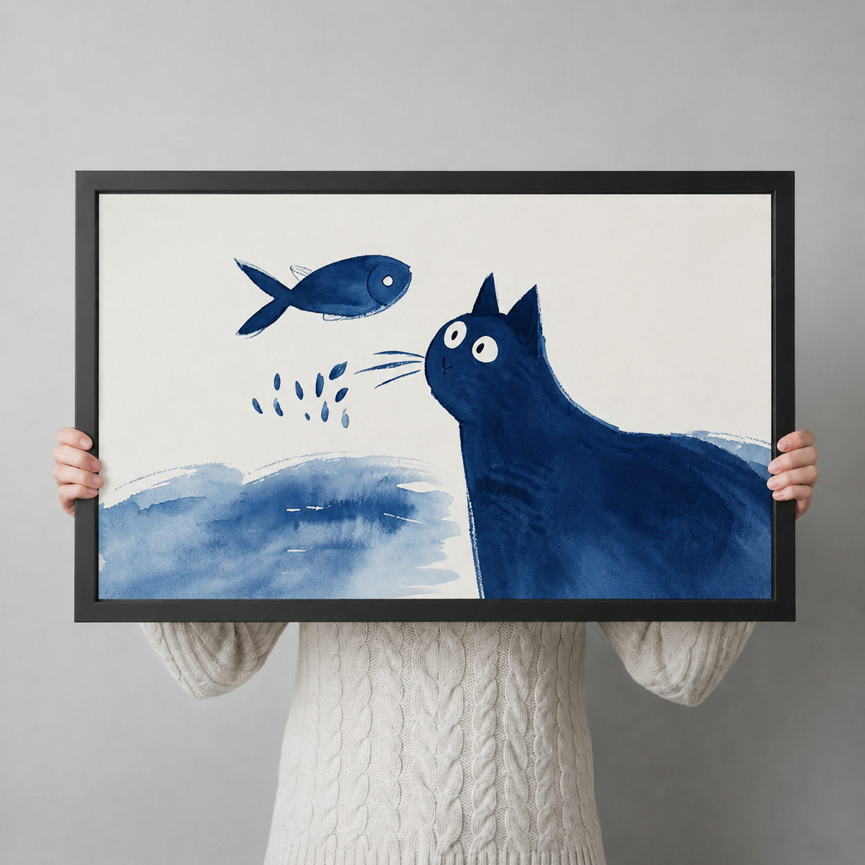 Large blue cat and fish watercolor art print with black frame held up for size reference, playful ink wash illustration poster