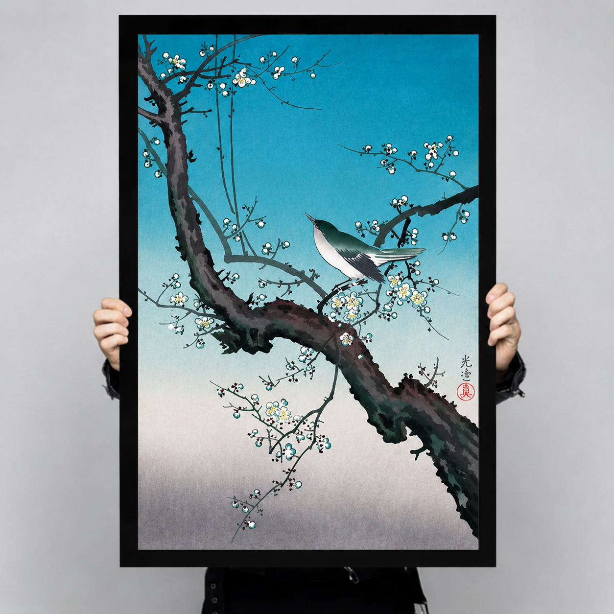 Large Japanese plum blossom bird art print with black frame held up for size reference, ukiyo-e inspired woodblock style nature poster