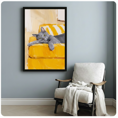 Black framed grey cat on yellow sofa canvas art print with loose brushstroke oil painting style on a light blue-grey wall beside a white linen armchair with draped throw