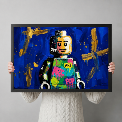 Person holding framed Lego street art print showing size reference, pop art style with blue and gold tones