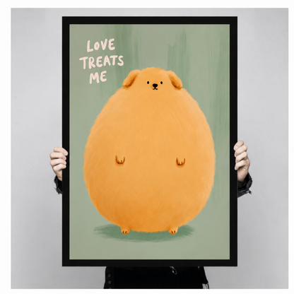 Close-up of a black framed art print featuring a round fluffy cartoon dog with "Love Treats Me" lettering on a soft green background, held up for display