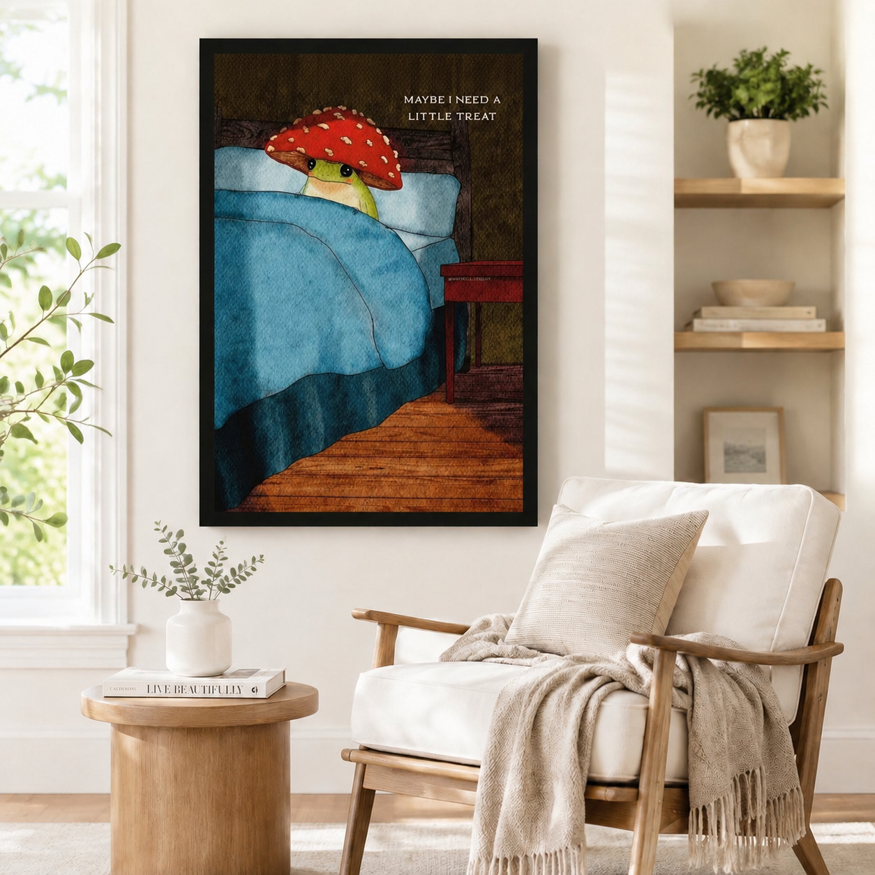 Black framed whimsical frog mushroom hat wall art print with "Maybe I Need A Little Treat" quote, styled in a Scandinavian reading nook with armchair and round side table