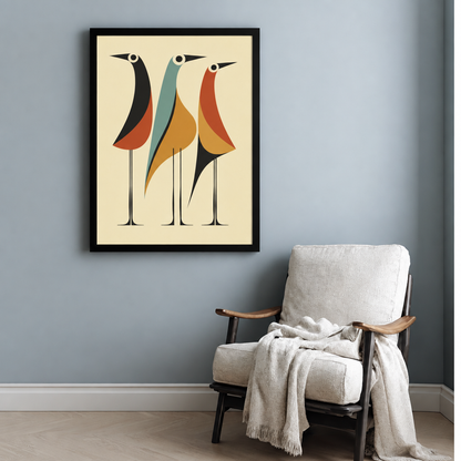 Mid-century modern illustration of three tall long-legged birds in geometric earth-tone shapes in black orange teal and rust on a cream background retro abstract bird wall art framed print beside armchair blue-gray wall