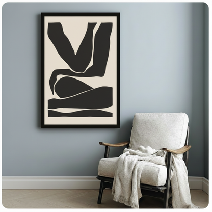 Black framed minimalist abstract figure print beside linen armchair on blue-grey wall - bold cream and black body silhouette canvas wall art for minimalist reading nook or bedroom decor