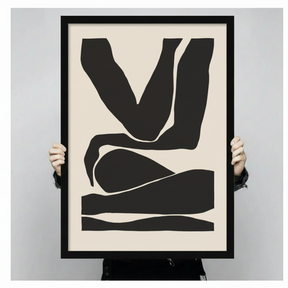 Person holding large framed minimalist abstract figure canvas print with both hands - close up view of bold black silhouette body form wall art on cream background with black frame finish
