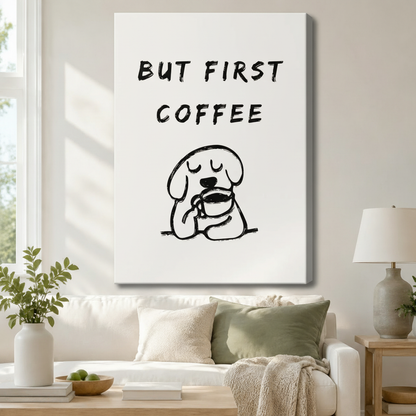 Stretched canvas wall art of a whimsical minimalist but first coffee quote print with bold hand-lettered text above a chubby cartoon dog with closed eyes contentedly holding a coffee mug in loose black line art on a clean white background, hung above a white sofa with sage green and cream pillows and a white ceramic table lamp in a bright airy living room