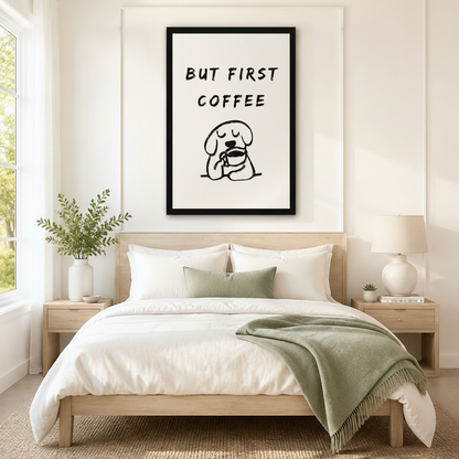 Black framed minimalist but first coffee sleepy dog canvas art with bold brush-lettered quote above a round cartoon dog with closed eyes hugging a coffee cup in loose black line art on a cream background, hung above a wooden bed frame in a sun-