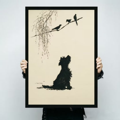 Person holding a black framed minimalist ink-style terrier dog silhouette gazing at three birds on willow branch art print on cream background against a light gray backdrop