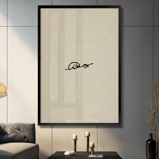 Framed minimalist dog and coffee cup single line wall art in a deep black frame on a warm cream background, displayed in a modern living room with a dark gray sofa, brass candle holders and a black ceramic vase