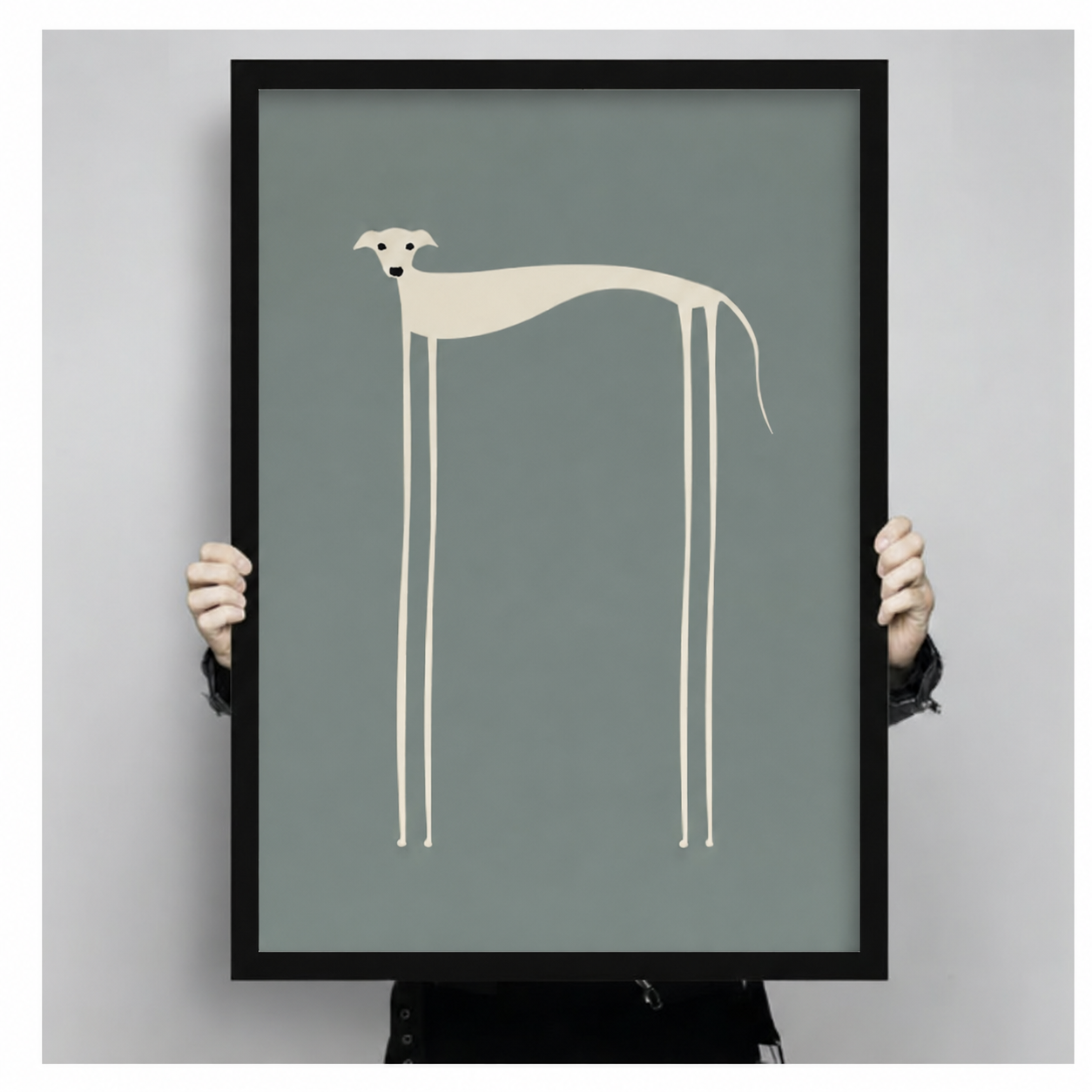 Person holding a large black-framed minimalist greyhound art print featuring a cream abstract dog with impossibly long legs on a muted teal-grey background, showcasing print size and quality