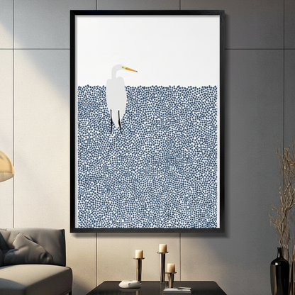 Framed minimalist white egret standing in dotted navy blue water wall art displayed above a console table with candlesticks in a contemporary dark grey living room