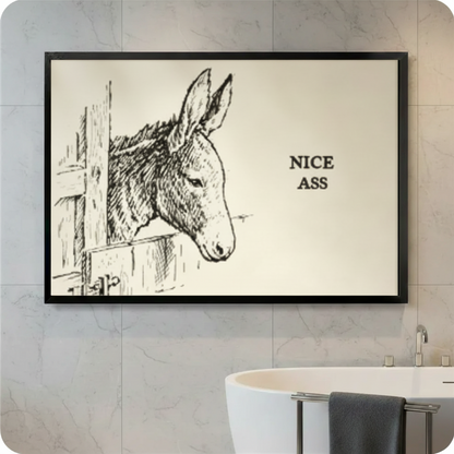 Black framed Nice Ass funny donkey sketch canvas wall art with cream background displayed in a bright white marble tile bathroom above a freestanding bathtub with black wall-mounted faucet