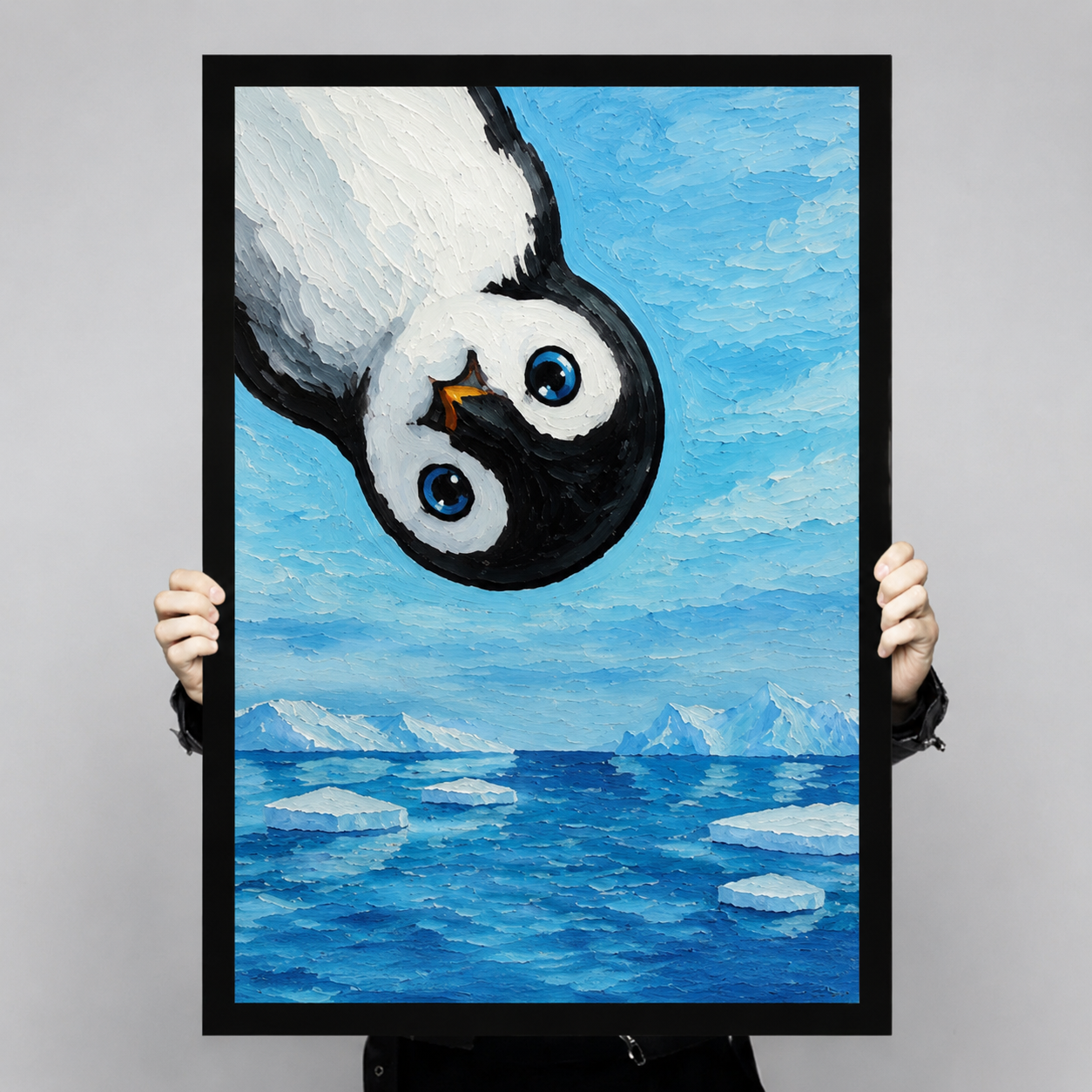 Person holding large framed penguin oil painting print showing full detail of upside-down penguin over Antarctic iceberg seascape